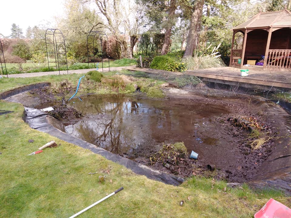 A garden pond which has been drained with a lot of sediment before being dredged