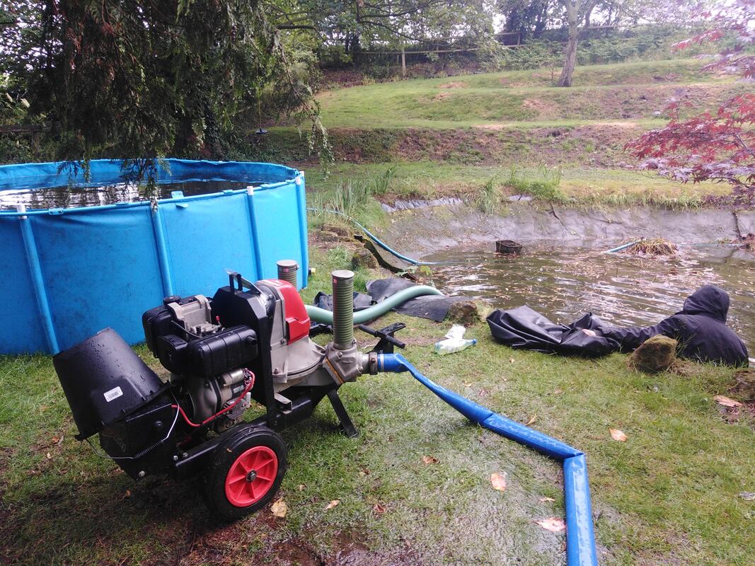 A natural garden pond with a holding pool and pump removing the water so it can be cleaned