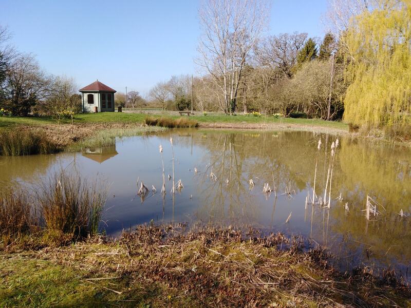 A natural pond that has been faithfully restored with a summer house in the background